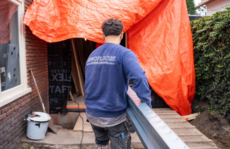 Monteur draagt een stalen ligger de woning in voor de nieuwe renovatievloer